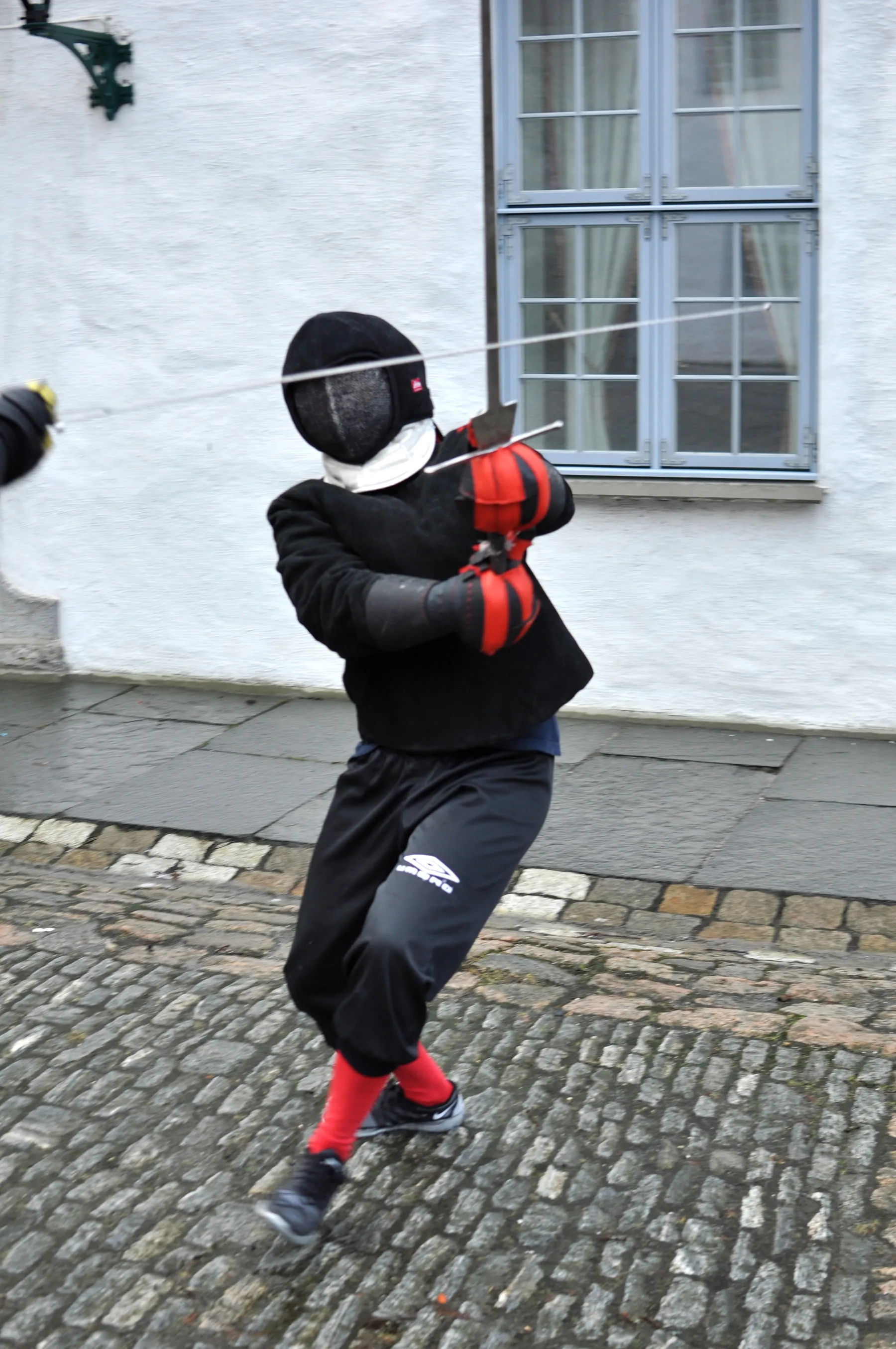 En fekter i maske midt i et hugg med langsverd.